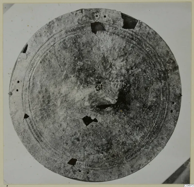 Round bronze object with concentric raised rings, a perforated rim and broken areas, from Idalion
