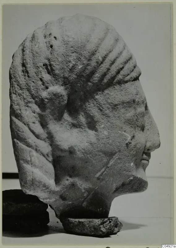 Limestone head from Kition in profile facing right, with ridged hair and a small stone base