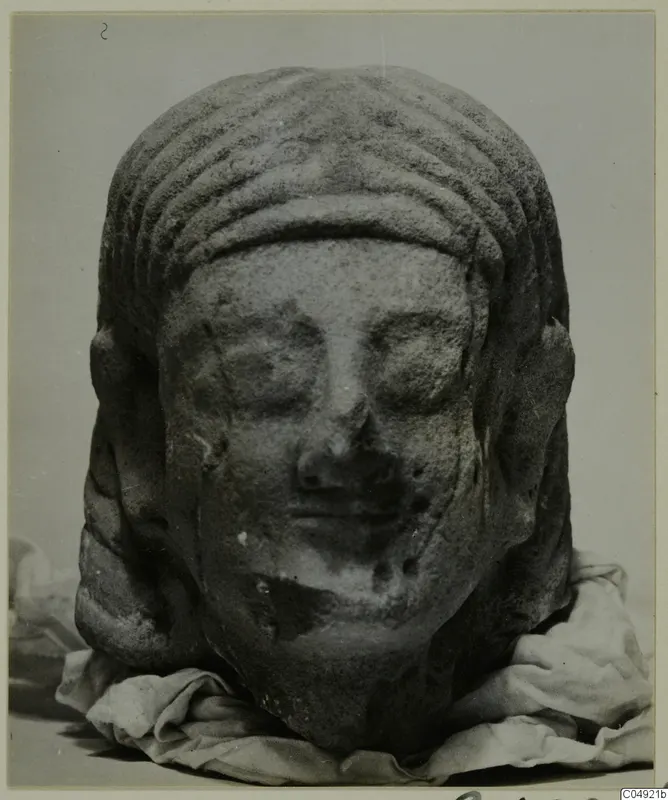 Limestone head from Kition, with ridged hair, photographed on folded cloth against a grey background.