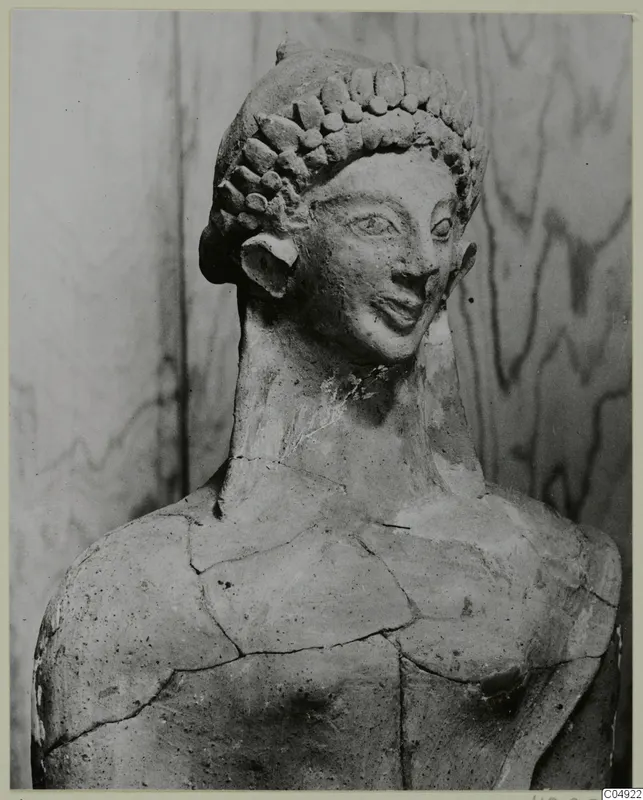 Terracotta head and upper torso of a statue, Mersinaki, with curled hair and cracks across the shoulders