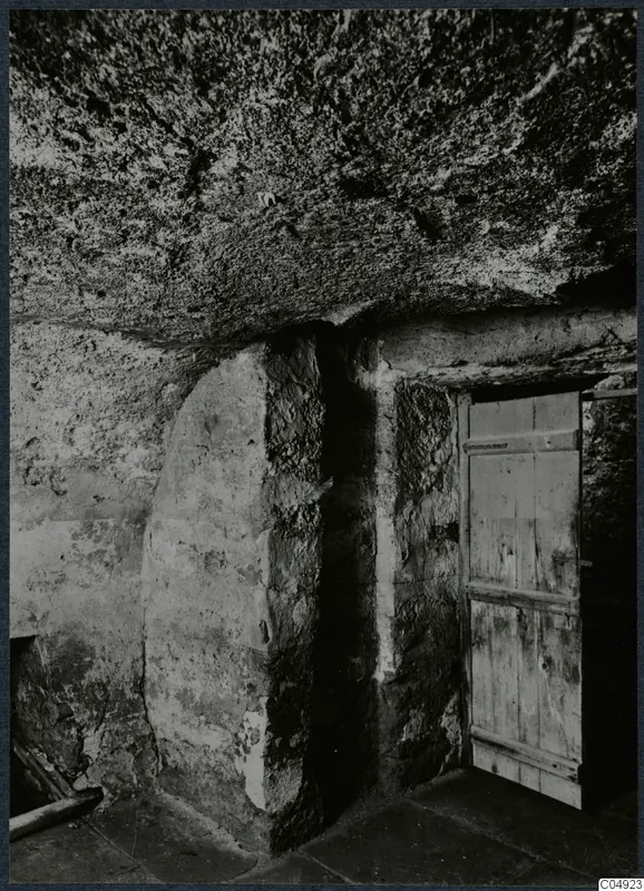 Interior of a built tomb chamber with a wooden door set into the stone wall