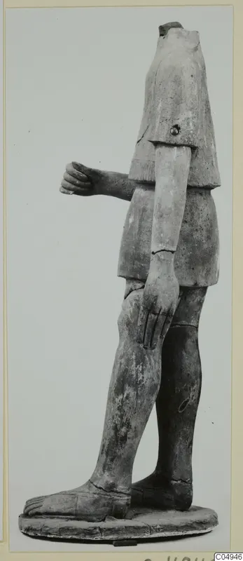 Headless terracotta statue of a standing figure on an oval base, one arm bent forward with the hand closed