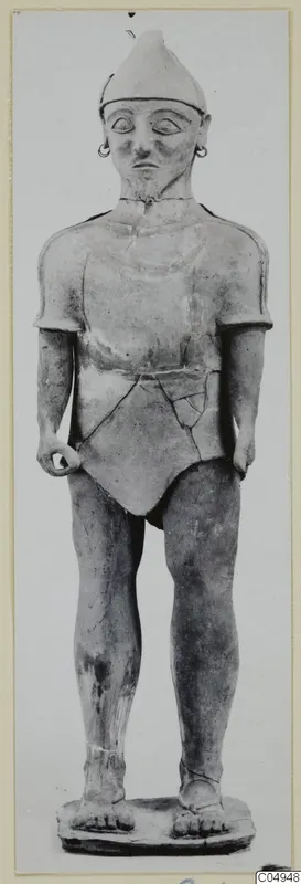Standing terracotta figure in a conical cap, with ring earrings and a short belted garment, on a flat base.