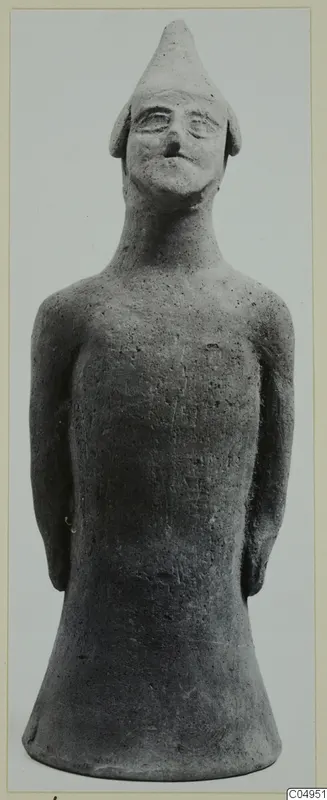 Terracotta figurine of a standing figure with a tall pointed cap and arms held at the sides.