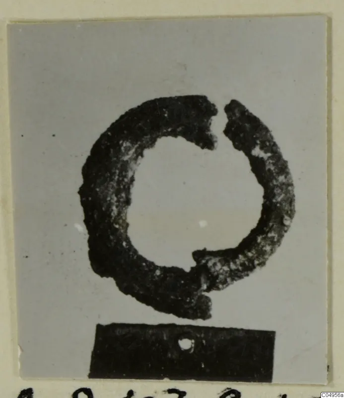 Corroded bronze ring or bracelet, broken open, photographed on a dark block; from Amathus.