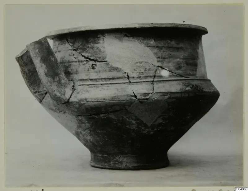 Pottery vessel from Milia with a wide flat rim, a ribbed shoulder and a strap handle, seen from the side