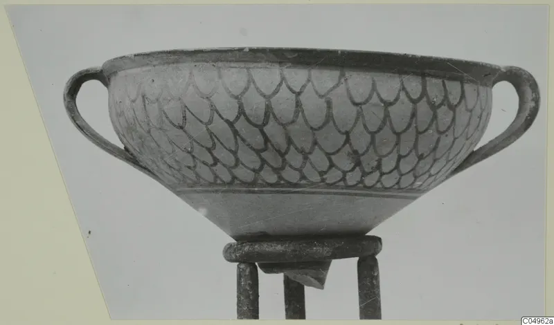 Two-handled bowl with a dark overlapping scale pattern, shown on a metal stand