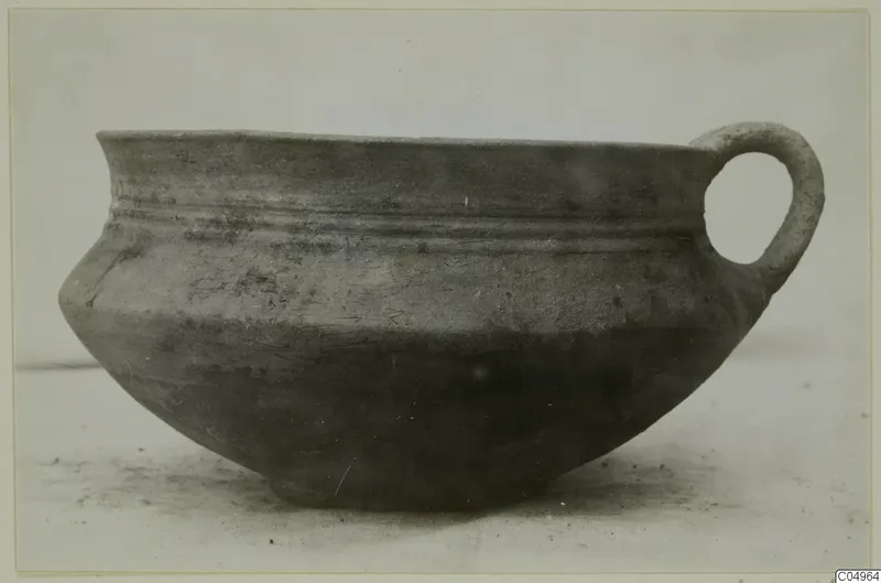 Pottery Bichrome Wheel-made bowl from Milia with a single loop handle, shown alone on a pale surface