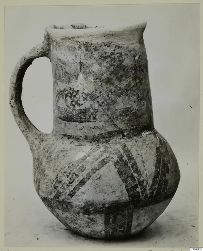 White Painted jug with a single handle and a flared neck, decorated with dark painted bands.