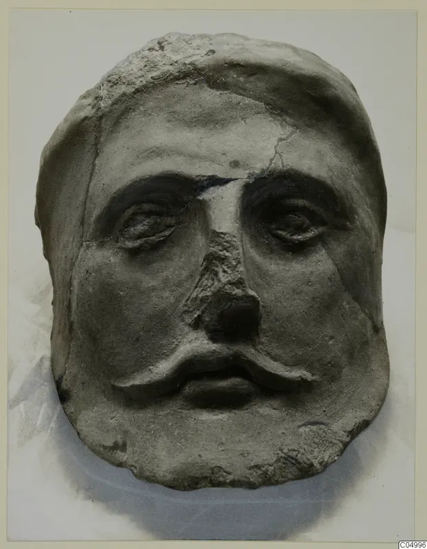 Face with a moustache from Mersinaki, grey-brown and cracked, shown frontally on a pale background