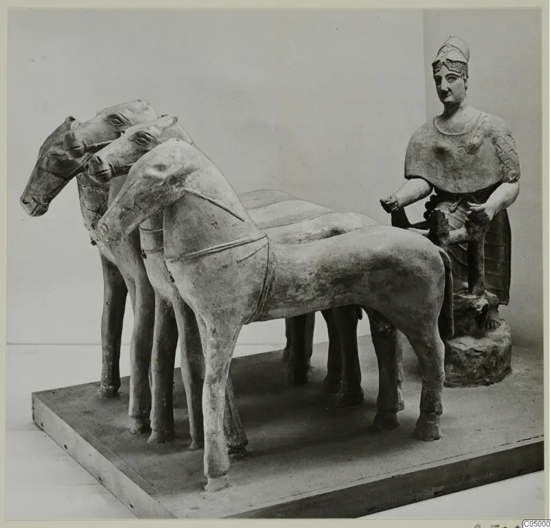 Terracotta group of horses harnessed in a row, with a seated figure in a helmet at the right, on a wooden plinth