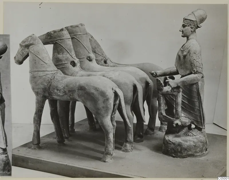 Terracotta group of a figure at a chariot rail behind a team of four horses on a flat plinth