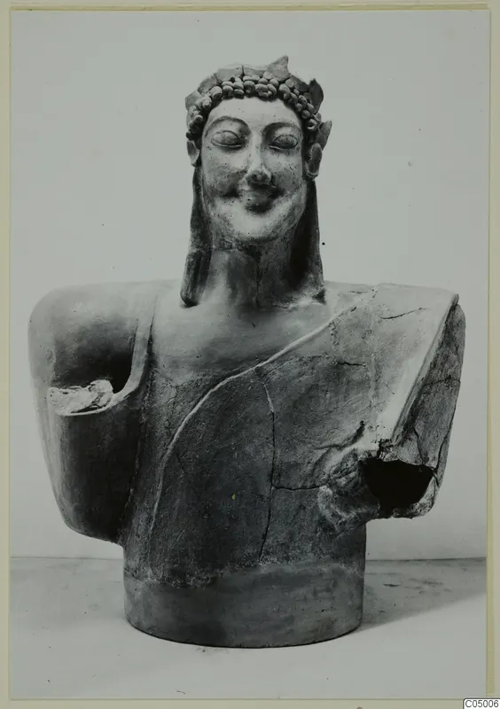 Terracotta bust of a smiling figure with closed eyes and a wreath, arms broken away, from Mersinaki
