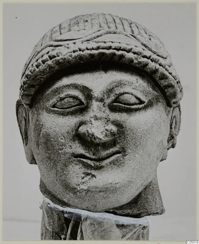 Limestone head and upper neck from Mersinaki, wearing a ridged cap, with a broken nose and a slight smile