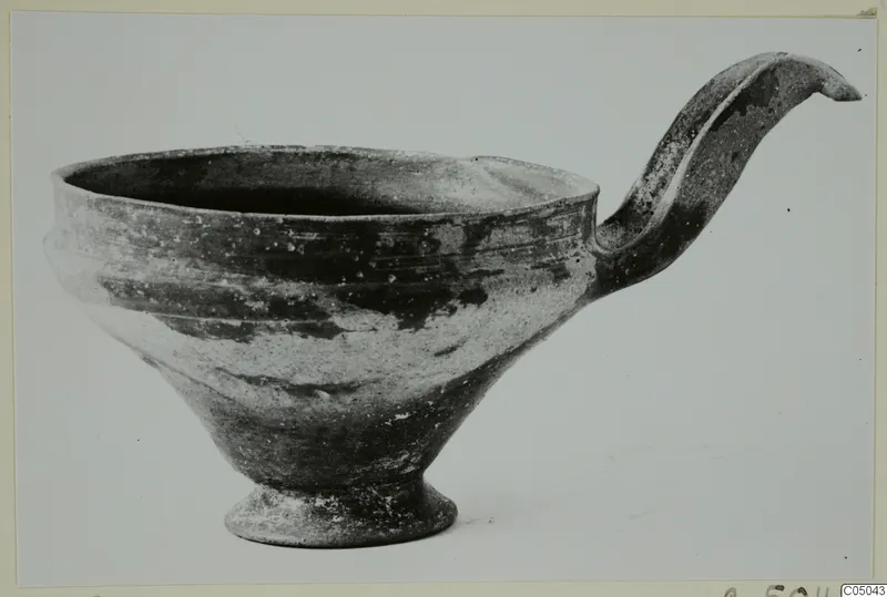 Base-Ring Ware bowl from Enkomi with a tall, curved handle rising from the rim.
