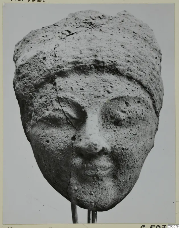 Terracotta head from Mersinaki with a close-fitting cap, cracked down the left cheek and broken at the top