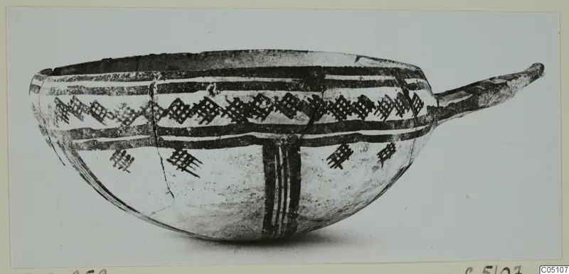 Pottery White Slip Ware bowl with a long handle, painted with dark bands and a lattice pattern
