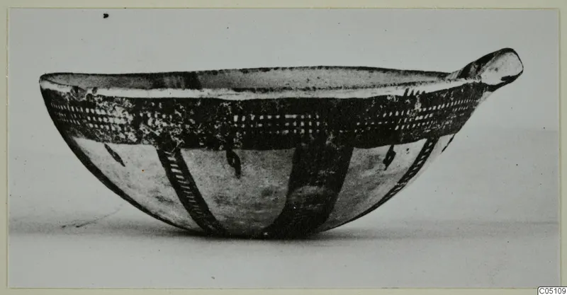 Pottery White Slip Ware bowl with dark painted bands and a small lug at one side, seen from the side