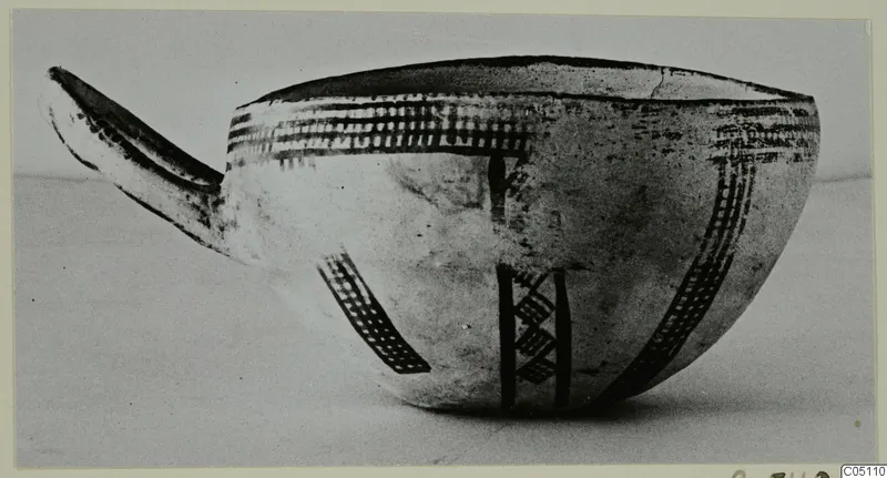 White Slip Ware bowl with a long spout, decorated with dark cross-hatched bands and vertical stripes