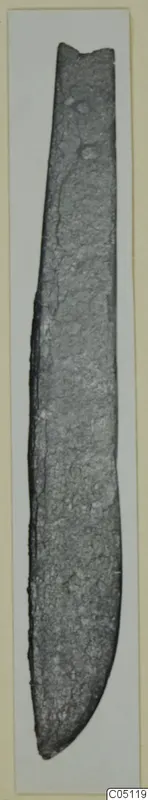 Iron knife from Idalion, a long narrow blade with a rounded point and corroded surface.