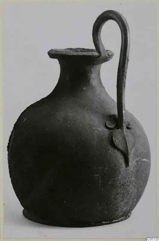 Bronze pot with a single arched handle and a flat, flaring rim, shown against a pale background