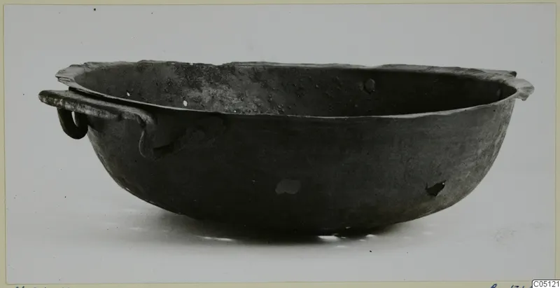 Shallow bowl with a flared rim and a ring-ended strap handle, shown in side view