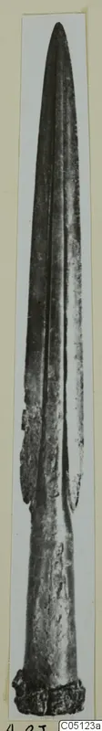Bronze weapon from Idalion: long tapering blade with a raised midrib and corroded base, shown upright.