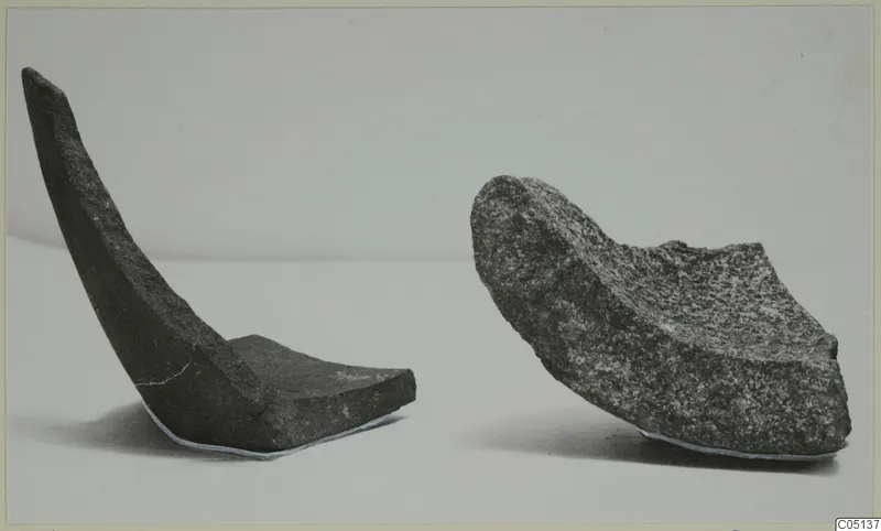 Two broken curved stone fragments from Petra tou Limniti on a pale surface