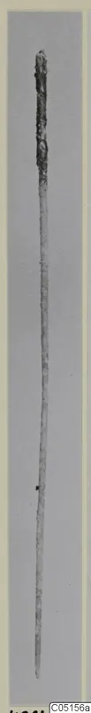 Bronze pin from the Kastros tombs at Lapithos, shown lying against a plain grey background.