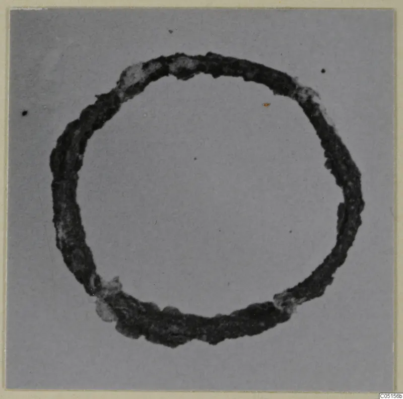 Corroded bronze ring, a personal adornment from Lapithos, photographed on a plain grey background