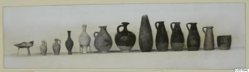Row of pottery vessels from Kountoura Trachonia Tomb 12: jugs, juglets, a dish on legs and a cup, set in a line.