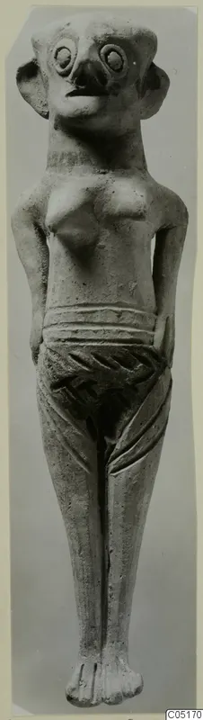 Standing figurine from Enkomi with large round eyes, a beak-like nose and protruding ears, shown frontally.