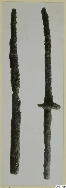 Two corroded iron weapons from the Kastros tombs at Lapithos, one with a cross-guard and grip