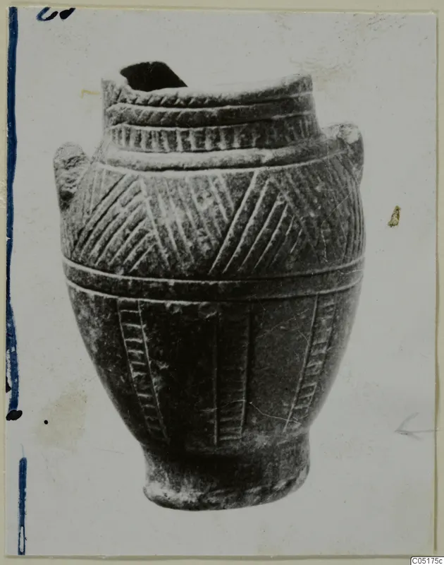 Jar with incised chevron and hatched bands and two lug handles, photographed against a plain light background.