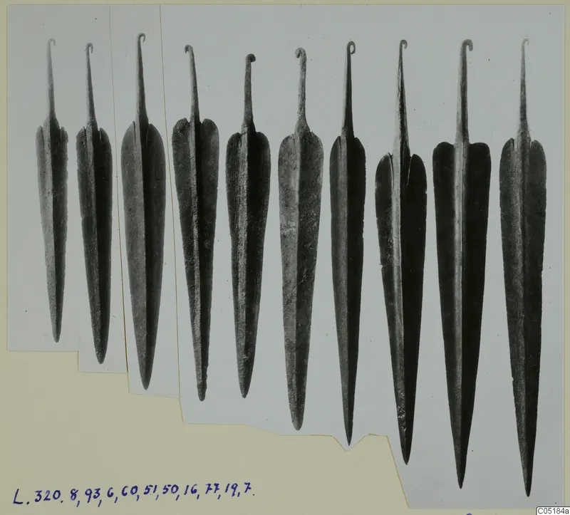 Row of metal weapon blades with looped tangs, photographed on a card mount, from Lapithos