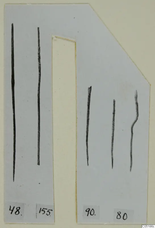 Five thin dark metal rods on a grey mounting card with number labels, bronze tools from Lapithos
