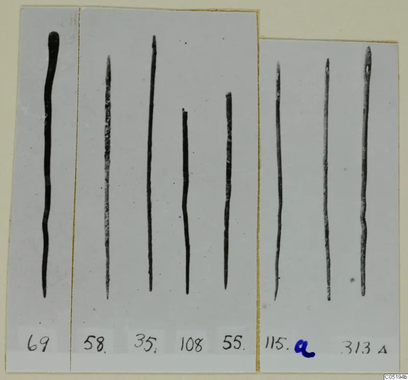 Eight long, thin metal rods on grey card mounts, numbered with labels, from Lapithos Tomb 313 A.