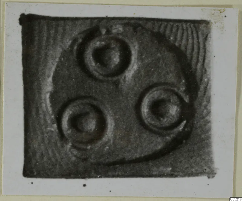 Glyptic: close view of a small seal face with three circular motifs set within a curved rim