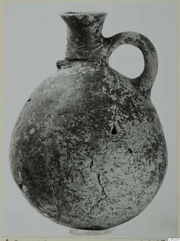 Pottery Black Slip Ware jug with a round body, flared neck and single loop handle