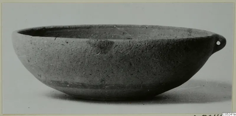 Pottery bowl-jar with a single pierced lug on one side of the rim, photographed on a plain background