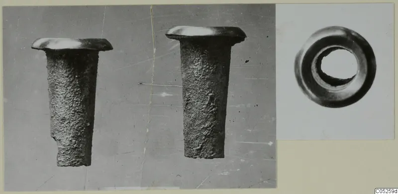 Two corroded metal tubular objects with flared rims, and an end view of a third ring-shaped object, photographed on a card