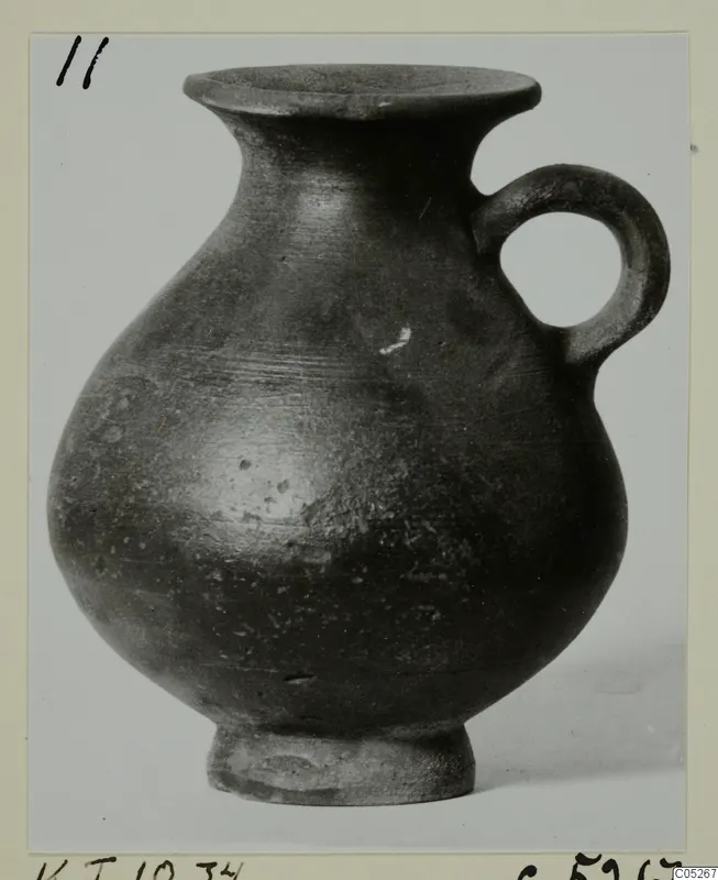 Dark-surfaced jug with a flared rim, globular body and single loop handle, from Kountoura Trachonia