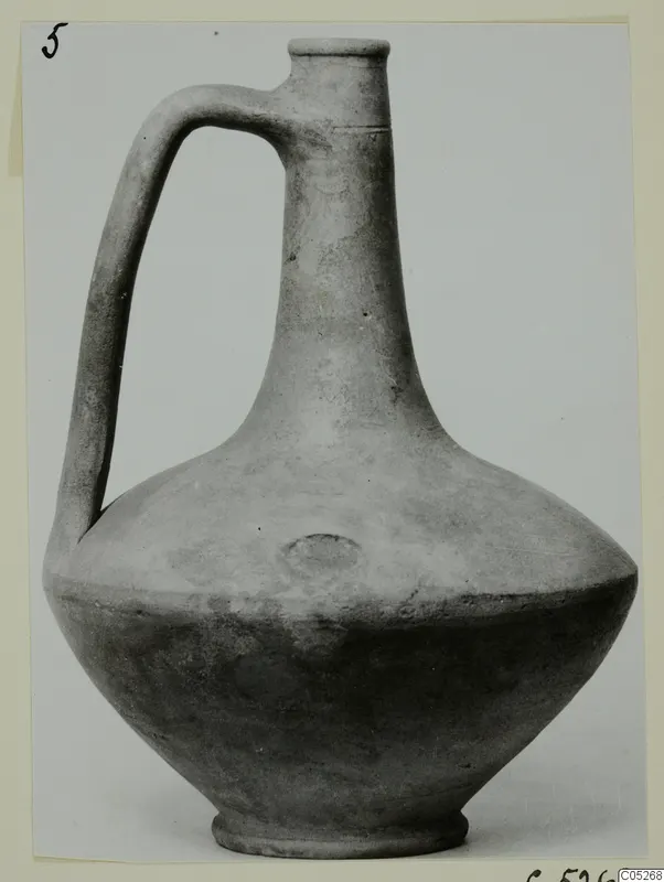 Jug with a single strap handle, a tall neck and a flared rim, shown in a photograph mounted on a card