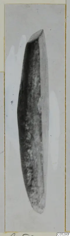 Elongated dark stone object tapering at both ends, shown on a mounted card from Kythrea.