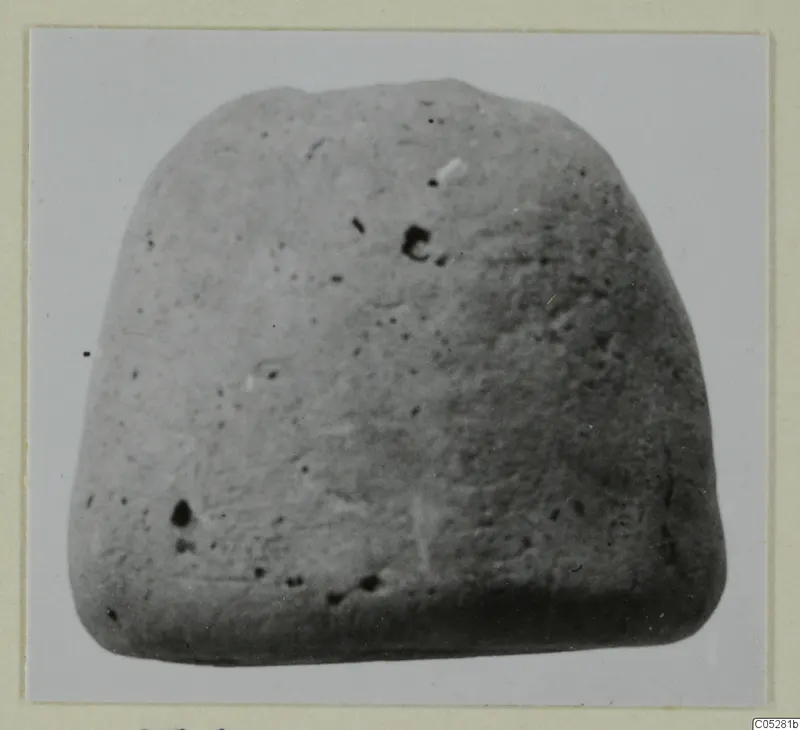 Grey block-shaped find from the Vrysi tou Barba tombs at Lapithos, photographed on a card mount