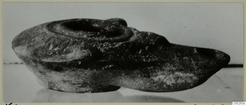 Terracotta lamp in side view, with a round filling hole on top and a long nozzle extending to the right.