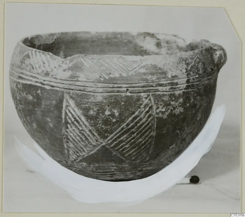 Pottery Red Polished III bowl with incised hatched and chevron decoration, photographed on a light surface