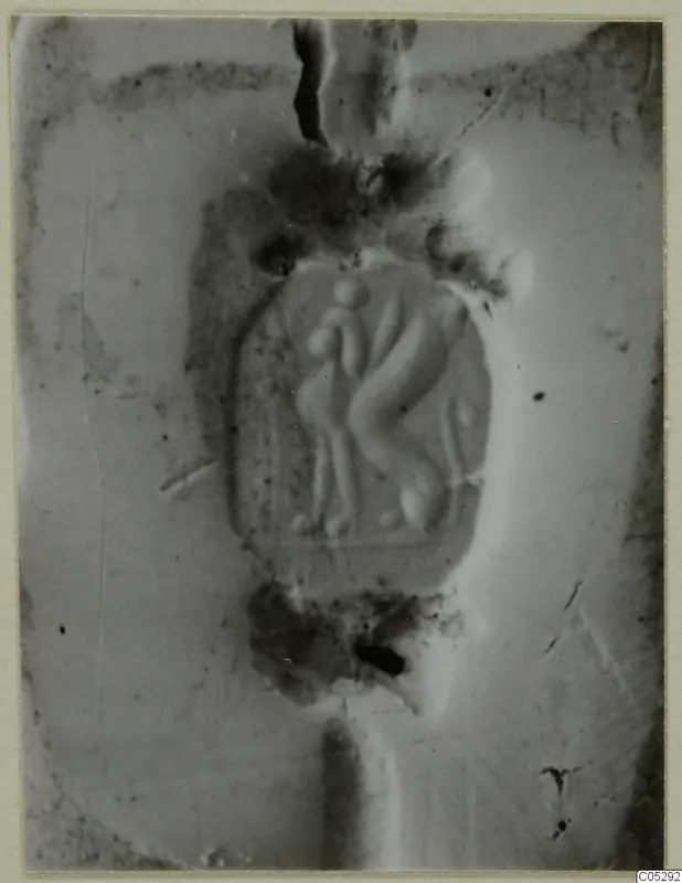 Glyptic object with two figures carved in relief at its centre, close view