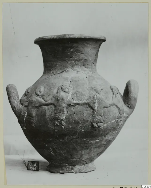 Two-handled pottery jar with relief figures of animals on its body, photographed against a plain backdrop