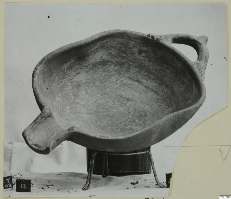 Pottery bowl with a loop handle and a small lug, standing on a wooden stand, from the Kastros tombs at Lapithos